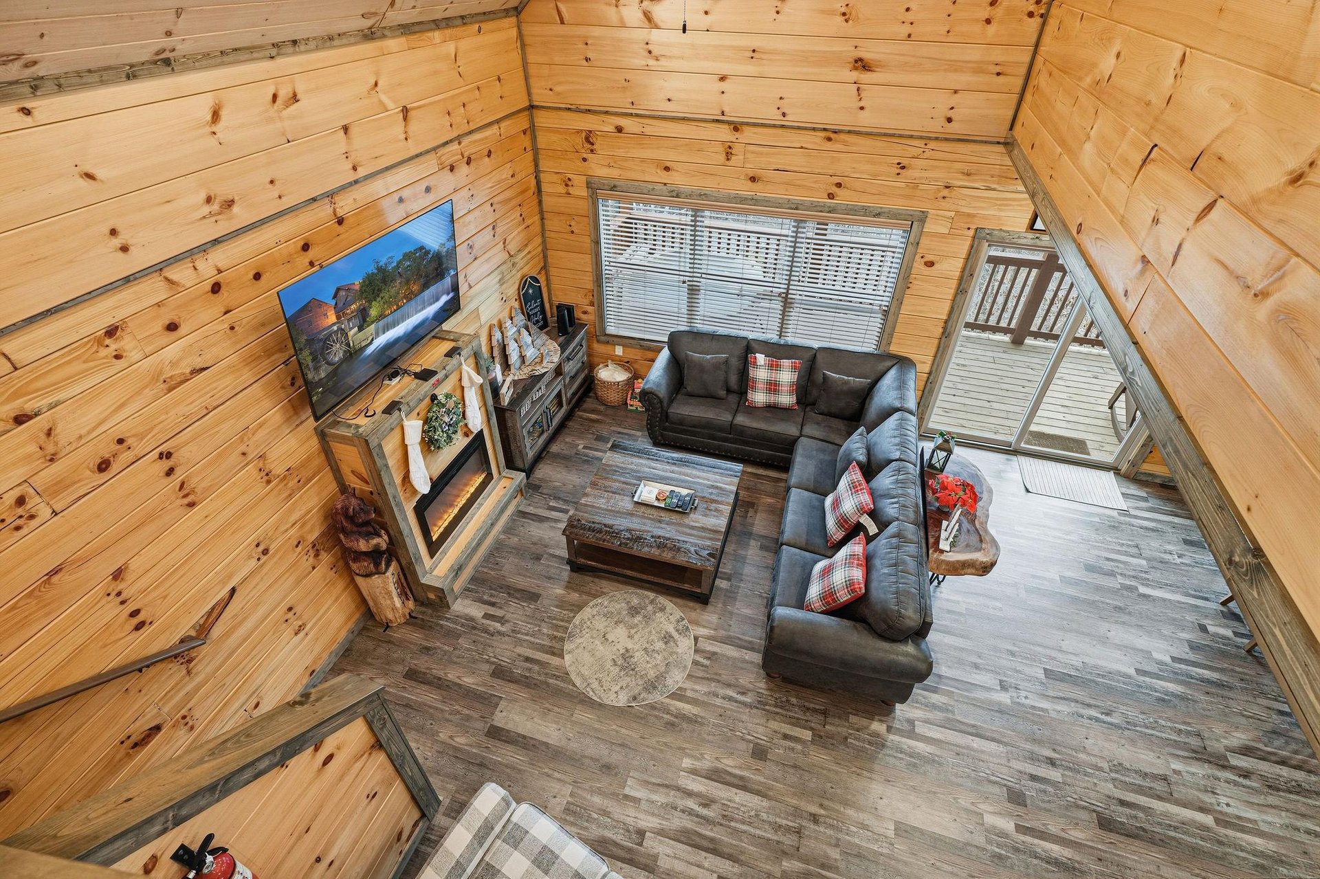 Unwind in your spacious living room featuring warm wood walls, cozy sectional seating, and modern entertainment for perfect mountain retreat evenings.