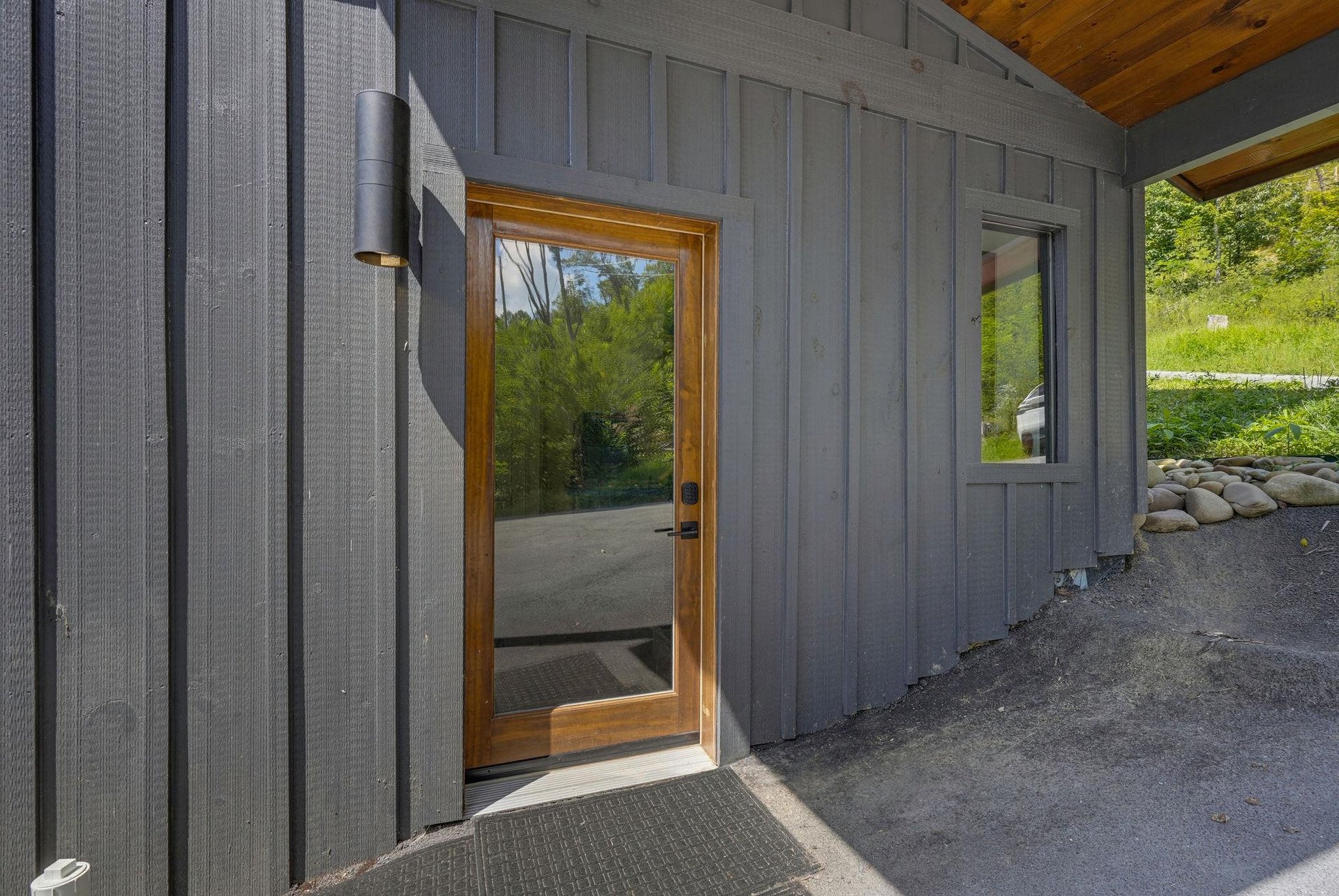 Contemporary entrance featuring a sleek glass door framed in natural wood, welcoming you into your peaceful retreat surrounded by lush greenery.