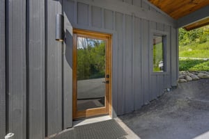 Contemporary entrance featuring a sleek glass door framed in natural wood, welcoming you into your peaceful retreat surrounded by lush greenery.