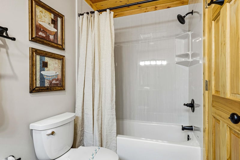 Your private bathroom features a tubshower combo with crisp white tile and a cozy rustic wood ceiling that adds mountain charm.