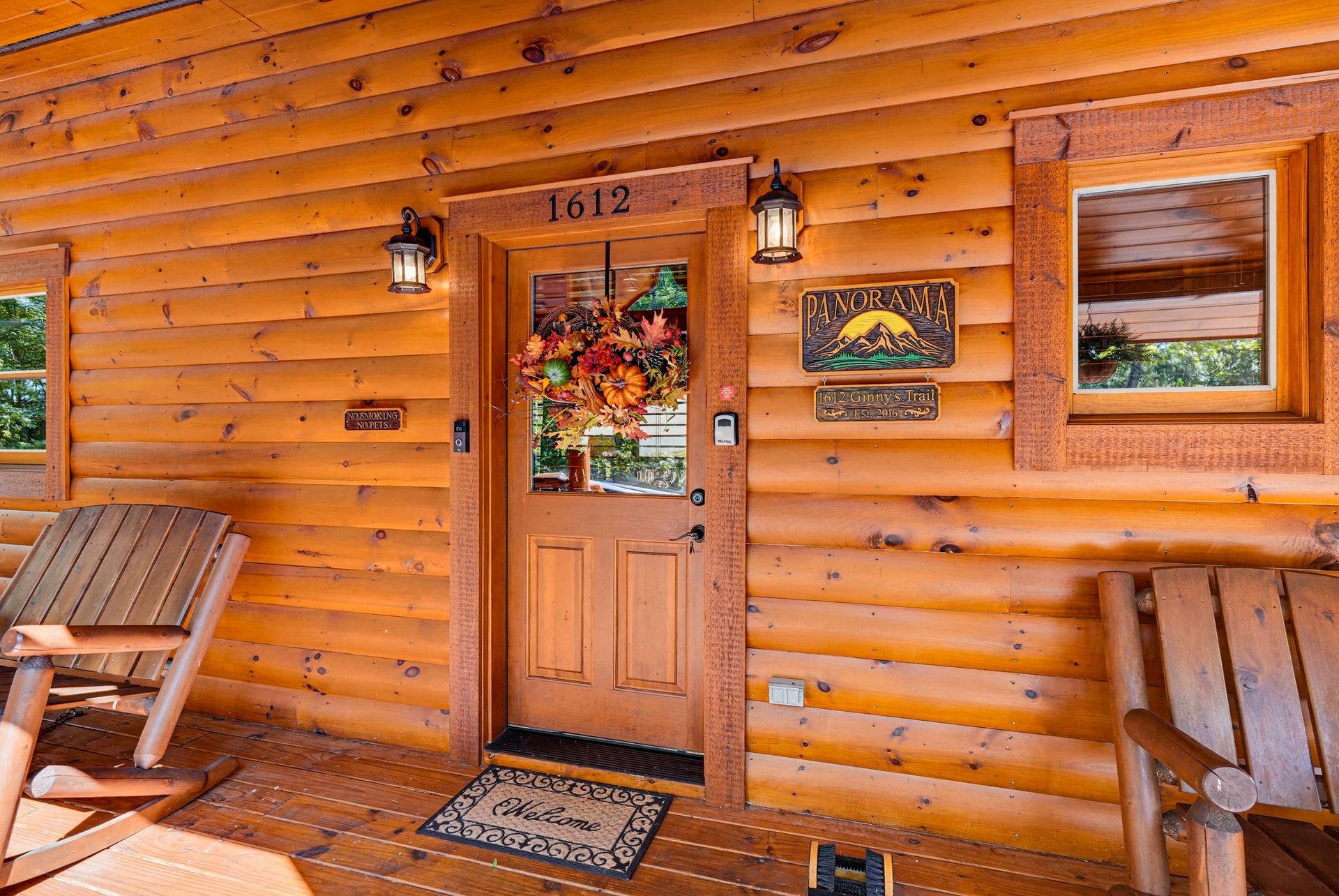 Your cabin getaway begins at this welcoming front porch with rustic wooden seating and warm lantern lighting—a charming arrival to your mountain retreat.