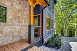 The property nestled in a peaceful wooded setting, blending stone and modern architecture with lush greenery surrounding your retreat.