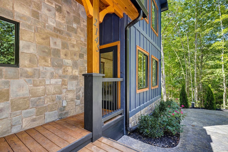 The property nestled in a peaceful wooded setting, blending stone and modern architecture with lush greenery surrounding your retreat.
