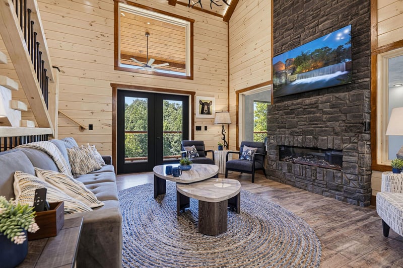 Sink into the plush sofa and feel the warmth of the stone fireplace as sunlight streams through tall windows, creating your perfect mountain retreat.