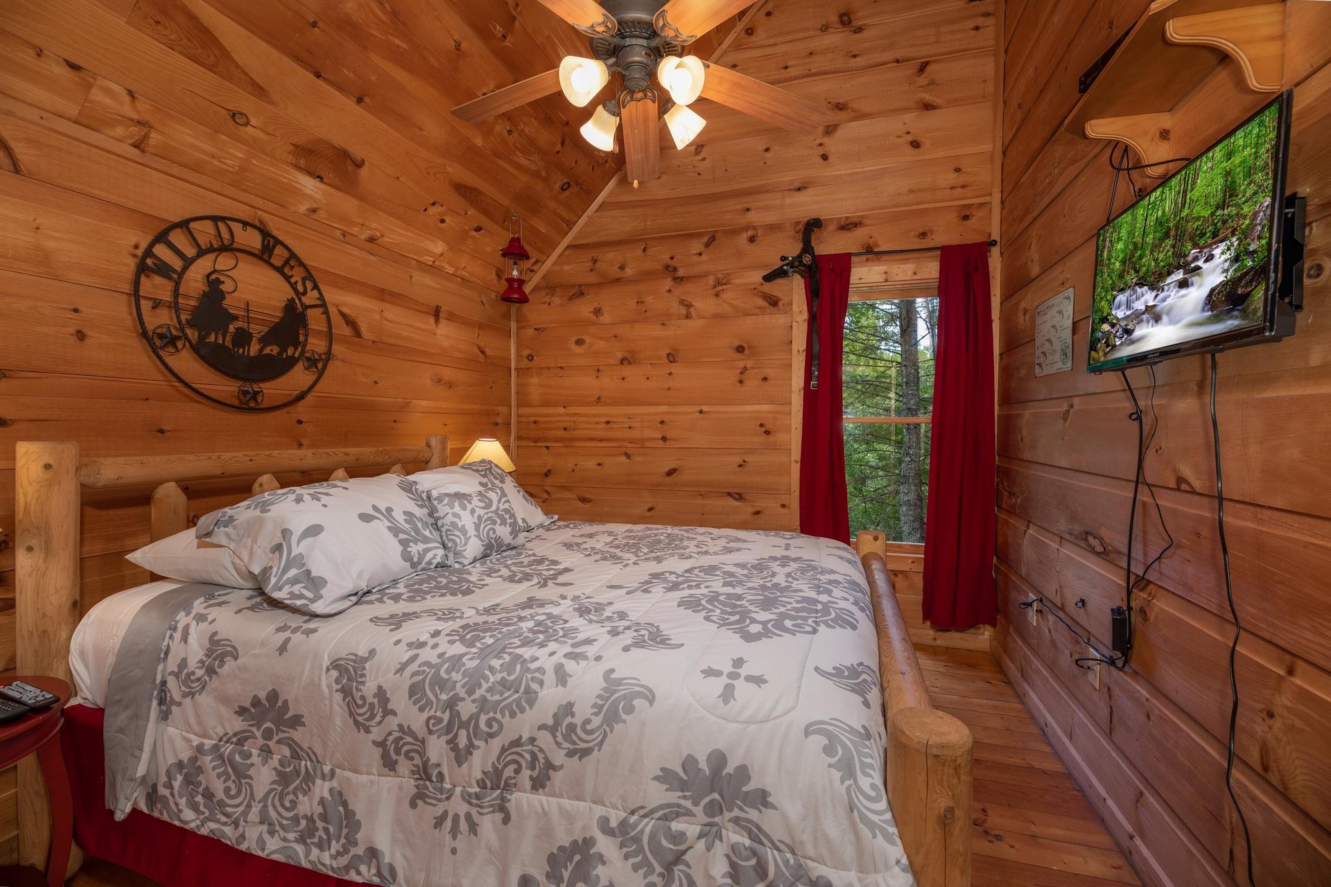 Bedroom with a king bed and TV at Logans Smoky Den, a 2 bedroom cabin rental located in Pigeon Forge