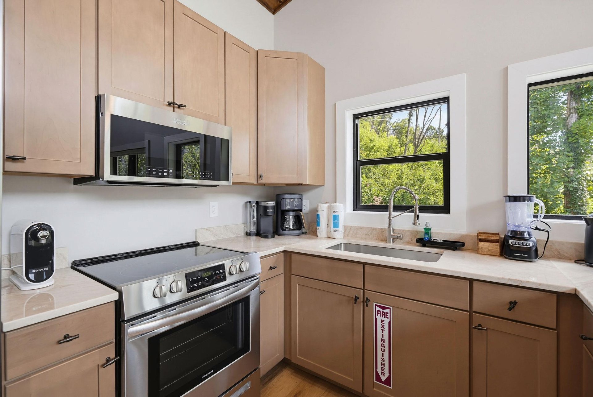 Prepare your favorite meals in this fully equipped kitchen with modern appliances and plenty of counter space. Natural light streams through the windows, highlighting the warm wood cabinets and creati