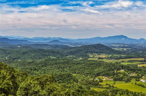 Sweeping mountain vistas stretch across forested hills and green valleys, offering a serene backdrop to the propertys natural surroundings.