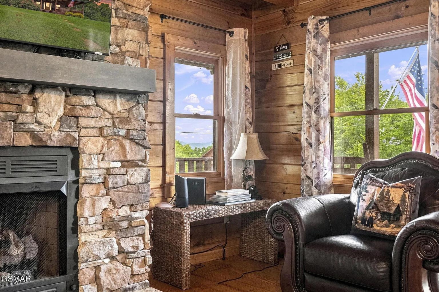 Curl up in your favorite armchair by the stone fireplace, where warm wood tones and sunlight streaming through the windows create a cozy mountain escape.