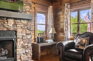 Curl up in your favorite armchair by the stone fireplace, where warm wood tones and sunlight streaming through the windows create a cozy mountain escape.