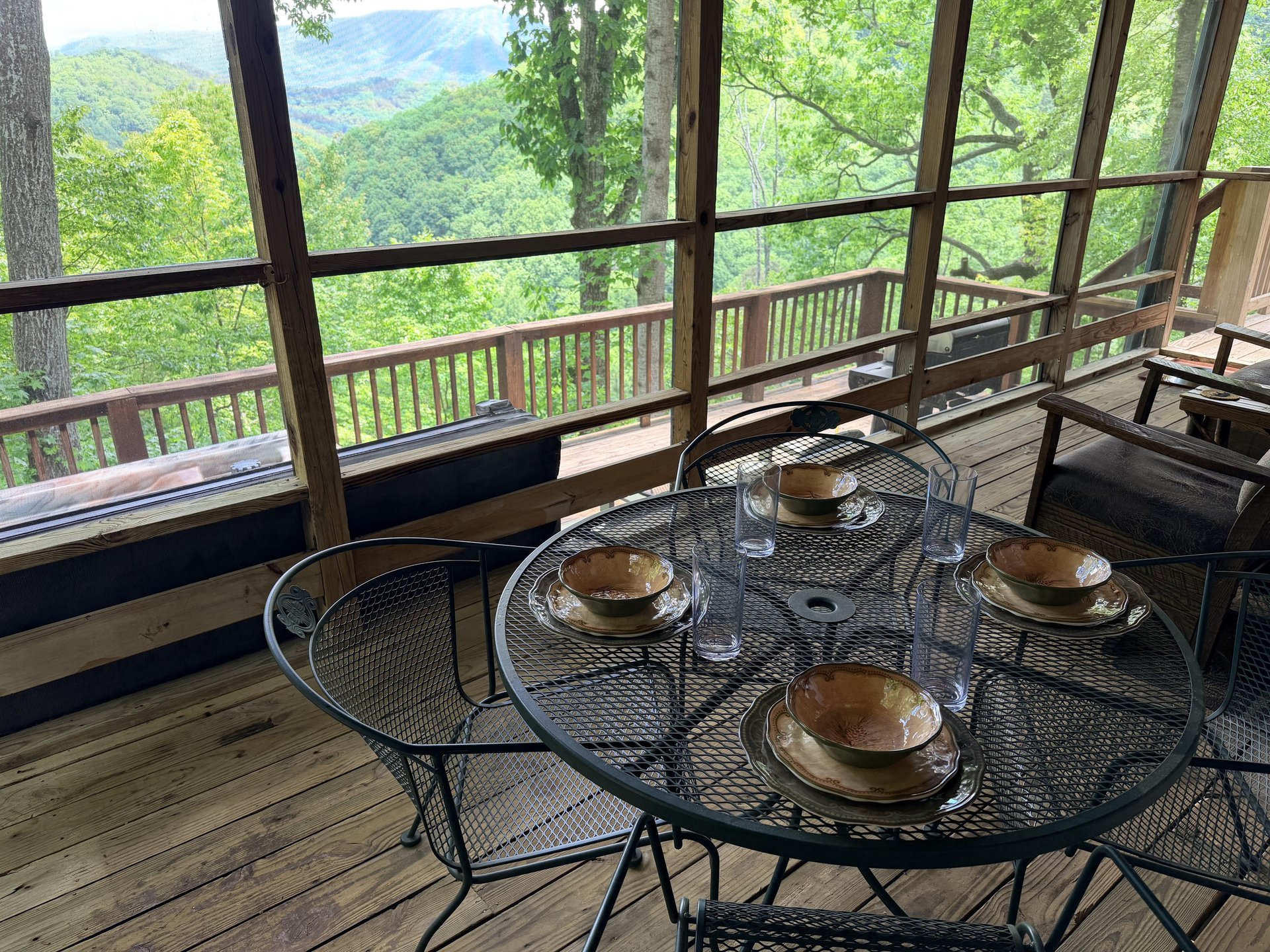 Sip your morning coffee at this screened porch dining table while taking in stunning mountain views through floortoceiling windows. A peaceful forest escape awaits you here.