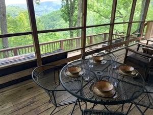 Sip your morning coffee at this screened porch dining table while taking in stunning mountain views through floortoceiling windows. A peaceful forest escape awaits you here.