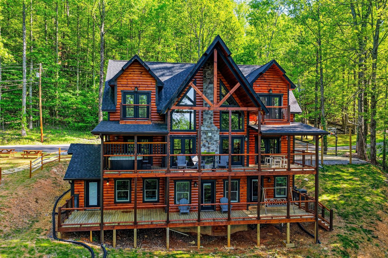Stunning log cabin retreat nestled among towering trees, featuring expansive decks and rustic charm in a peaceful forest setting.