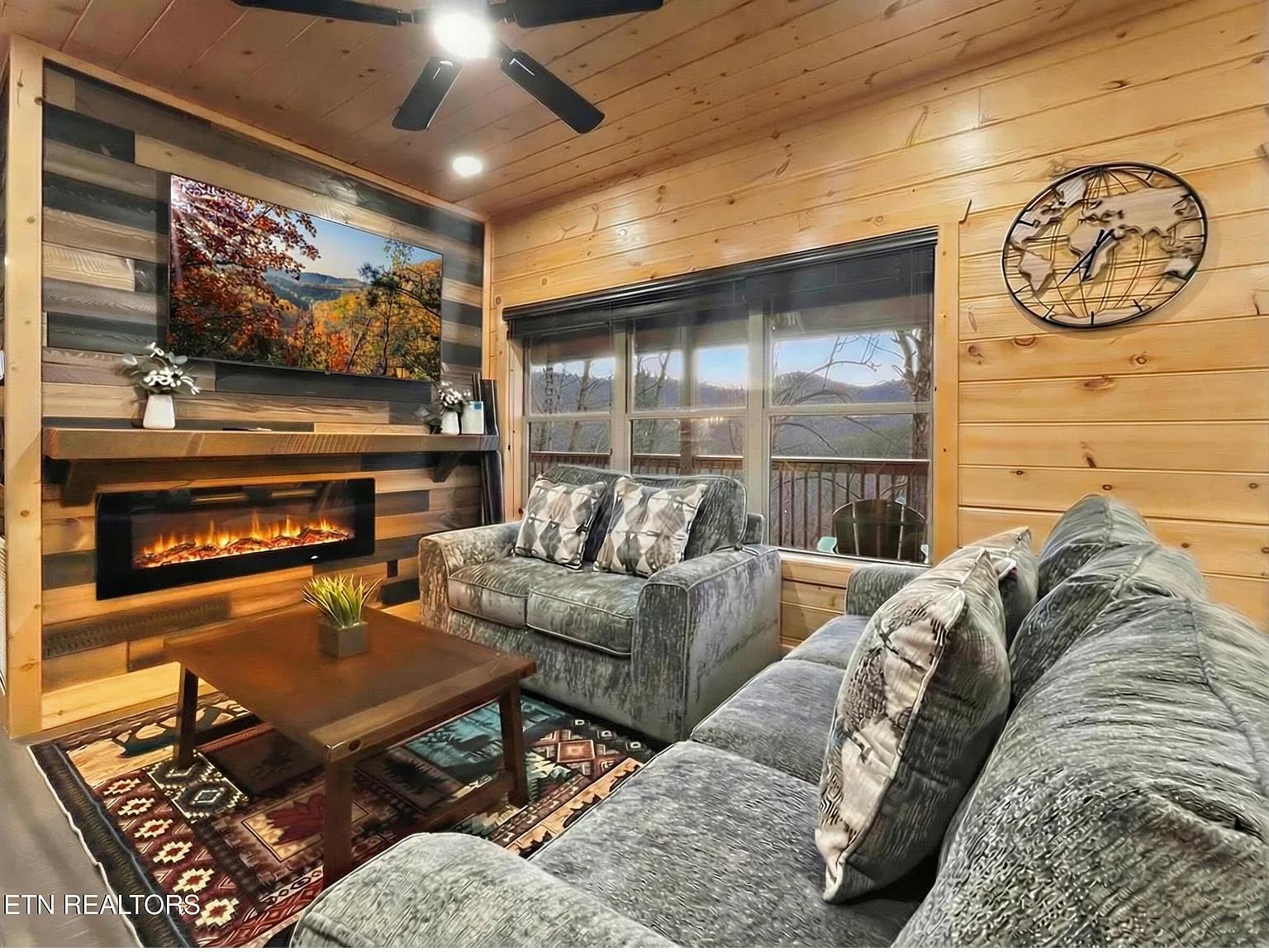 Cozy up by your crackling fireplace in this rustic living room, where plush seating and warm wood walls create the perfect mountain retreat.