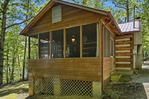 A charming wood cabin nestled in lush forest, featuring screened porch and rustic details. Natural beauty surrounds this peaceful retreat, perfect for a woodland getaway.