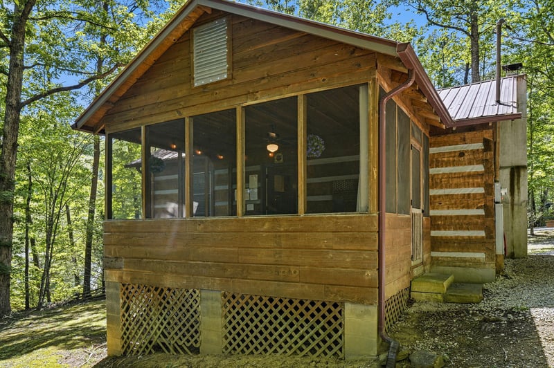 A charming wood cabin nestled in lush forest, featuring screened porch and rustic details. Natural beauty surrounds this peaceful retreat, perfect for a woodland getaway.