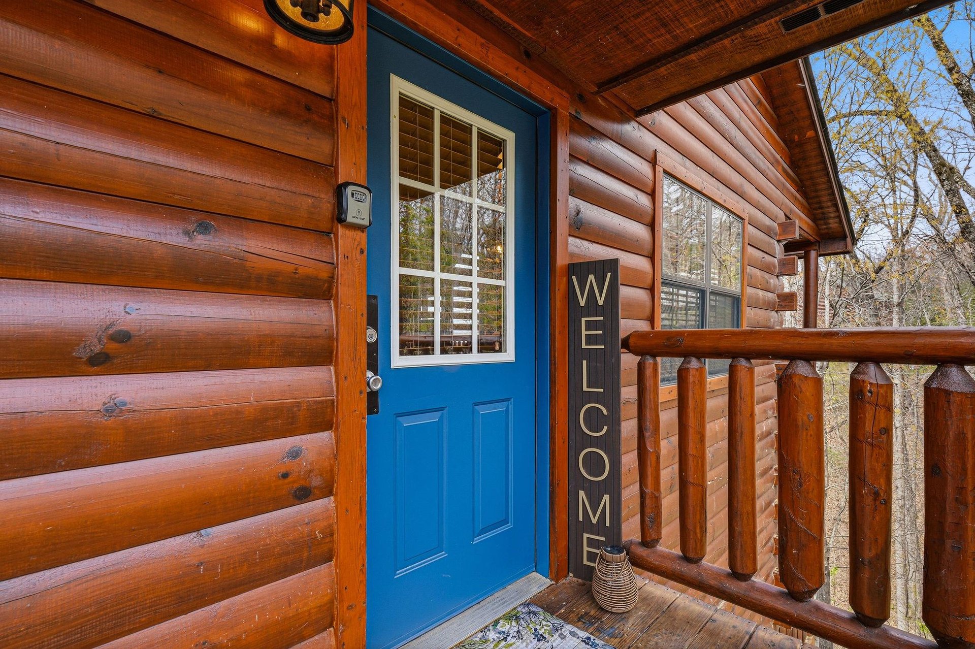 A charming log cabin entrance awaits your arrival, featuring warm wood tones and a welcoming blue door.