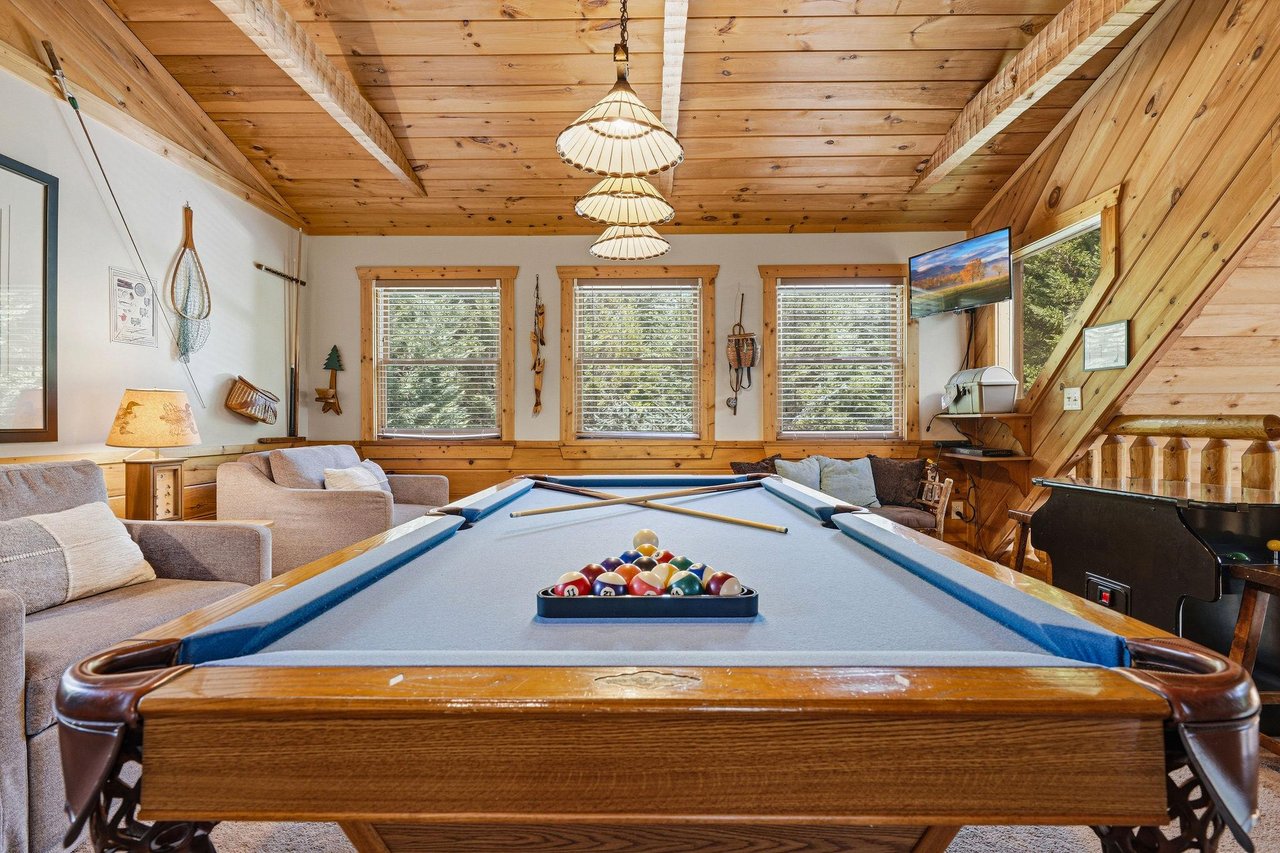 Challenge your friends to a game in this inviting loftstyle game room with soaring wood ceilings, cozy seating, and natural light streaming through the windows.