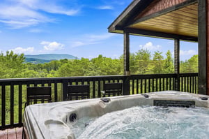 Soak in the bubbling hot tub on your covered deck while gazing at the rolling forested mountains under a clear blue sky.