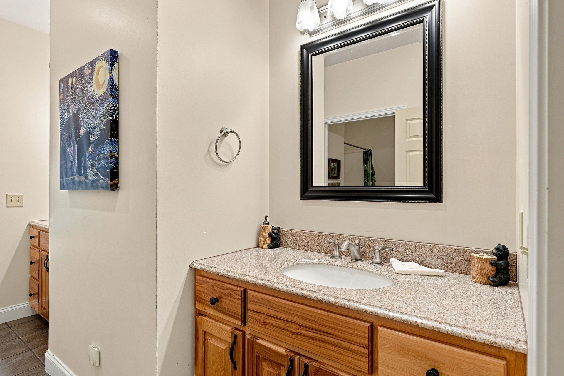 Your private bathroom features warm wood cabinetry, speckled granite countertops, and thoughtful touches like coastal artwork and decorative accents that make freshening up feel effortless.