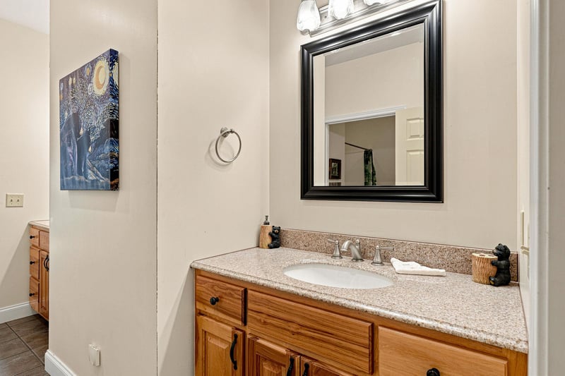 Your private bathroom features warm wood cabinetry, speckled granite countertops, and thoughtful touches like coastal artwork and decorative accents that make freshening up feel effortless.