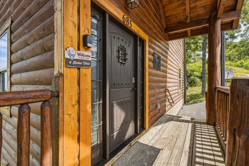 The log cabin entrance features a charming covered porch with rustic wooden beams, offering a welcoming arrival experience to your woodland retreat.