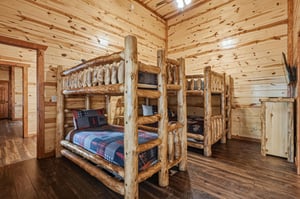 Cozy up in rustic log bunk beds surrounded by warm wood walls that create your perfect mountain retreat atmosphere.
