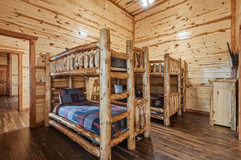 Cozy up in rustic log bunk beds surrounded by warm wood walls that create your perfect mountain retreat atmosphere.