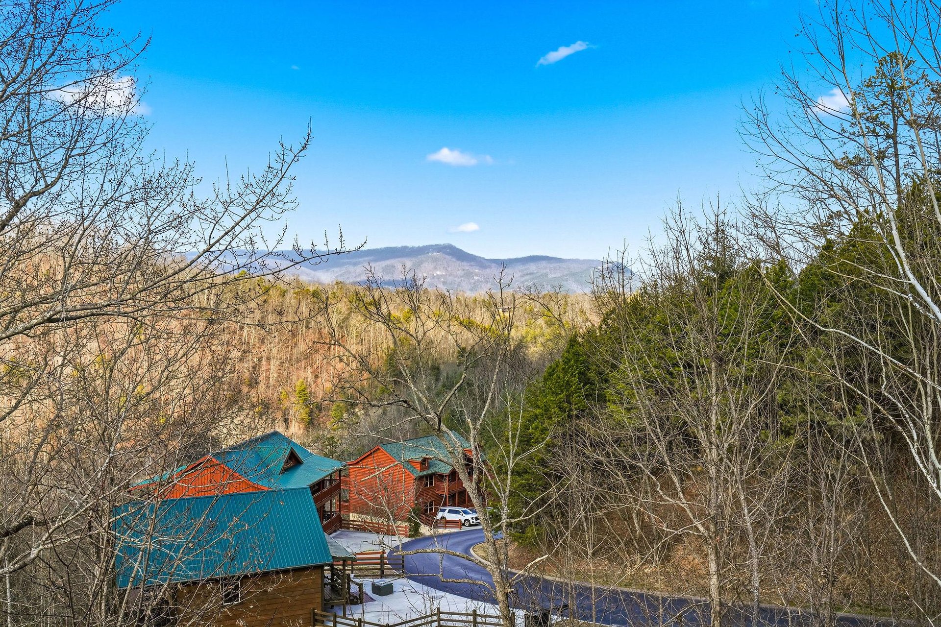 Mountain cabin retreat nestled among trees with stunning views of rolling hills and blue skies in a peaceful natural setting.