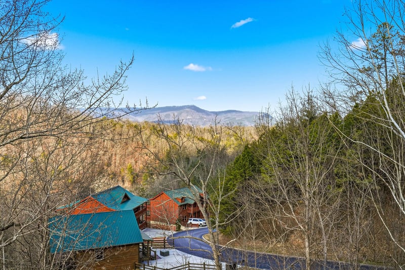 Mountain cabin retreat nestled among trees with stunning views of rolling hills and blue skies in a peaceful natural setting.