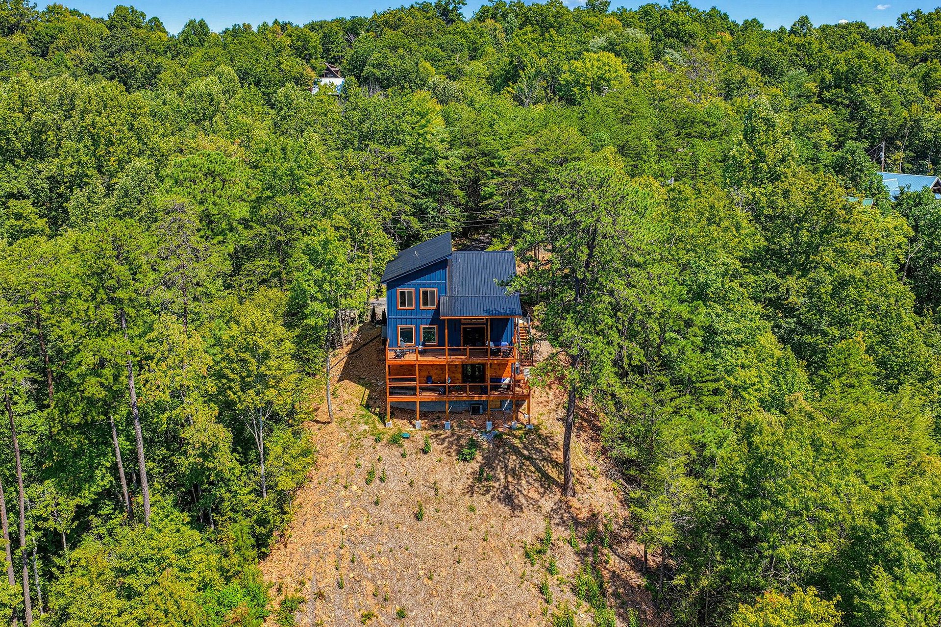 This striking blue cabin is nestled in lush forest, offering a secluded woodland retreat with expansive outdoor decks for relaxing and taking in the natural surroundings.