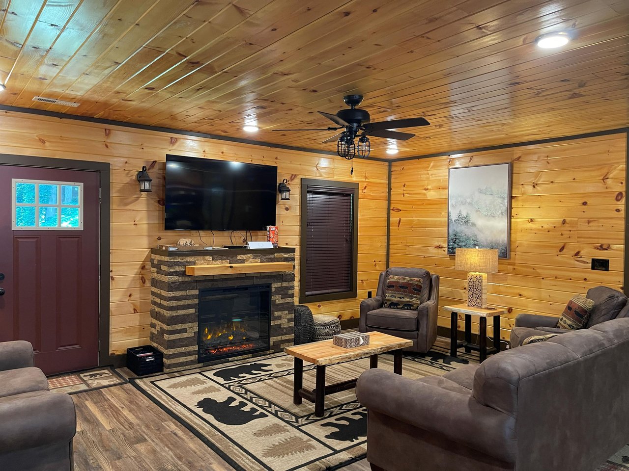Unwind in your rustic mountain retreat with plush seating, a crackling stone fireplace, and warm woodpaneled walls that make every moment feel cozy and inviting.