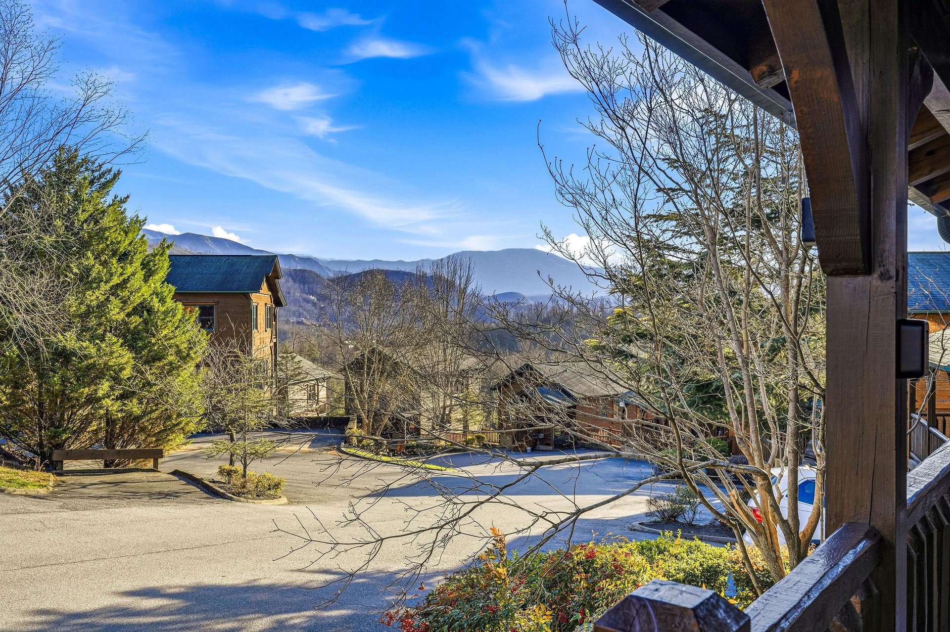 Sweeping mountain vistas visible from the propertys covered porch, with nearby cabins nestled among winter trees and scenic alpine peaks in the distance.