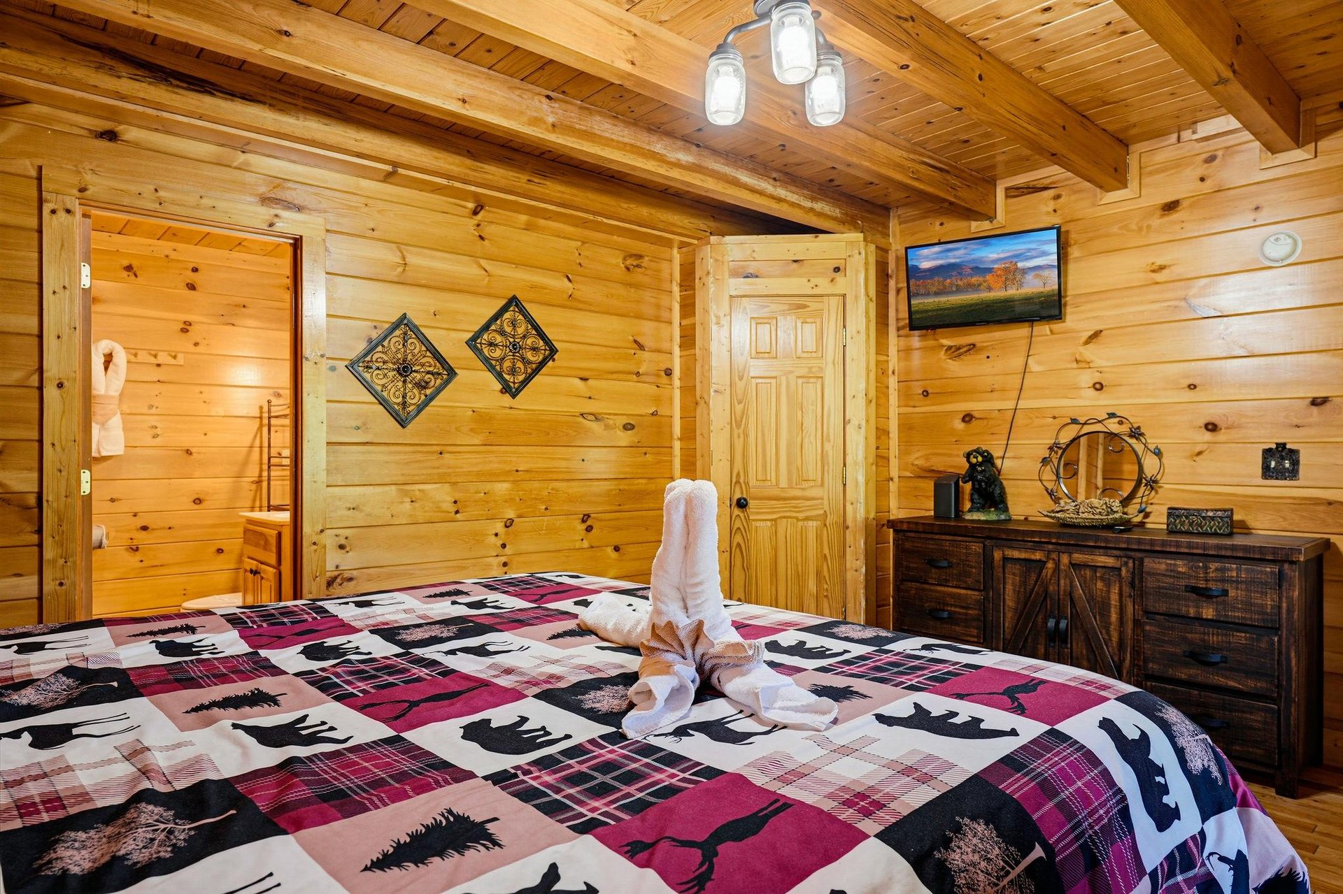 Unwind in your cozy cabin bedroom, where rustic wood walls and a plush bearprint quilt invite peaceful mountain dreams after a day of adventure.