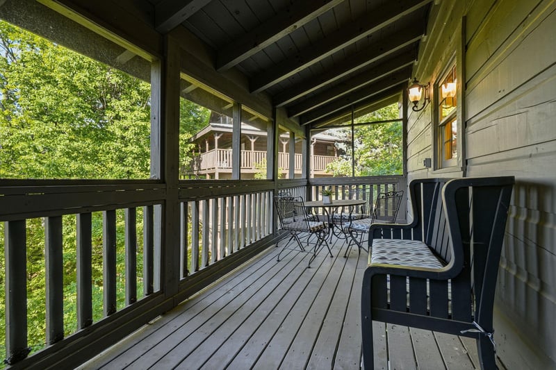 Your private covered deck invites morning coffee moments surrounded by lush treetops and peaceful cabin views.