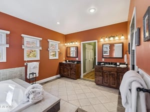 Step into your spacious bathroom retreat with warm terracotta walls, dual vanities with elegant lighting, and plush towels waiting for you. Sunlight streams through the windows as you prepare for the