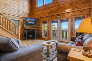 Unwind in your spacious living room with soaring ceilings, a cozy stone fireplace, and floortoceiling windows framing stunning mountain views—your perfect retreat awaits.