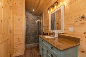 Single vanity sink with walk in shower with stone wall