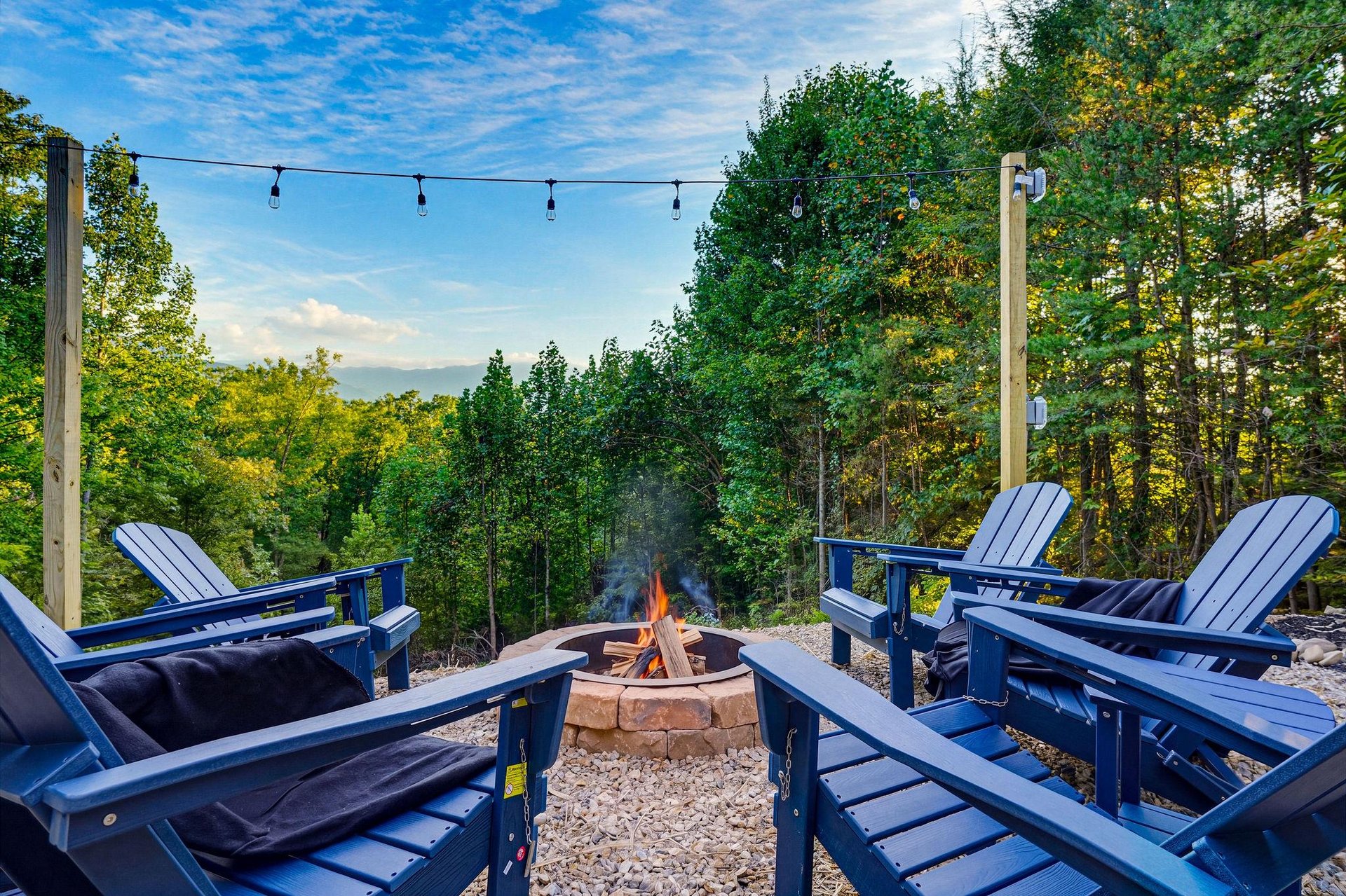 Gather around the fire pit in your private outdoor space, where Adirondack chairs face lush woods and string lights set a peaceful evening mood.