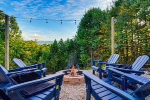 Gather around the fire pit in your private outdoor space, where Adirondack chairs face lush woods and string lights set a peaceful evening mood.