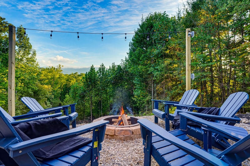 Gather around the fire pit in your private outdoor space, where Adirondack chairs face lush woods and string lights set a peaceful evening mood.