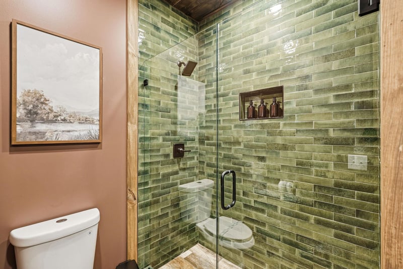Step into your spalike bathroom with stunning green subway tile shower, rainfall showerhead, and luxurious glass enclosure for ultimate relaxation.