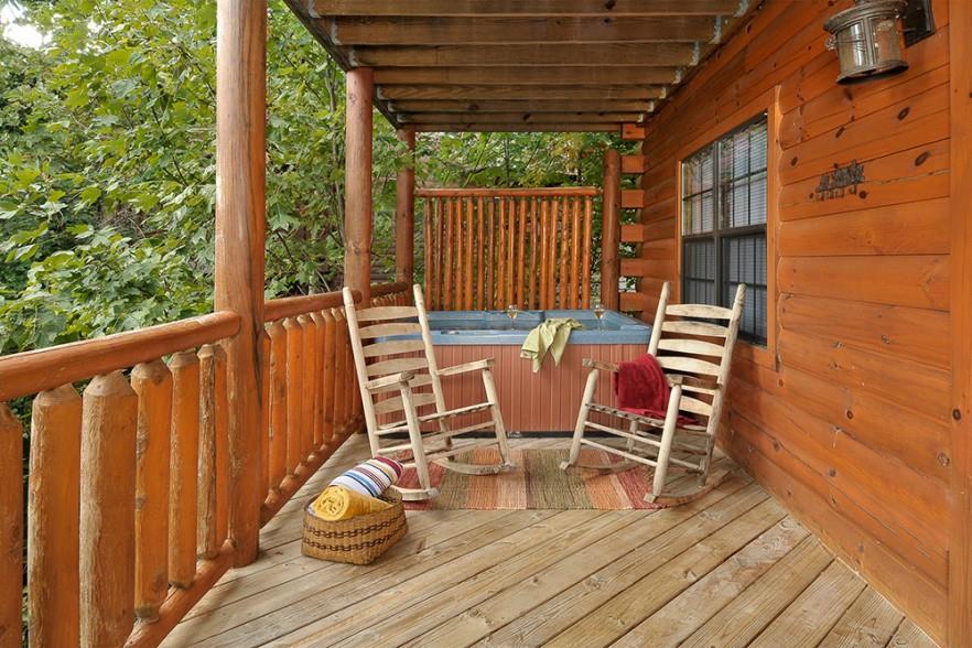 Hot tub and rocking chairs on a covered deck at Kick Back  Relax A 4 bedroom cabin rental located in Pigeon Forge
