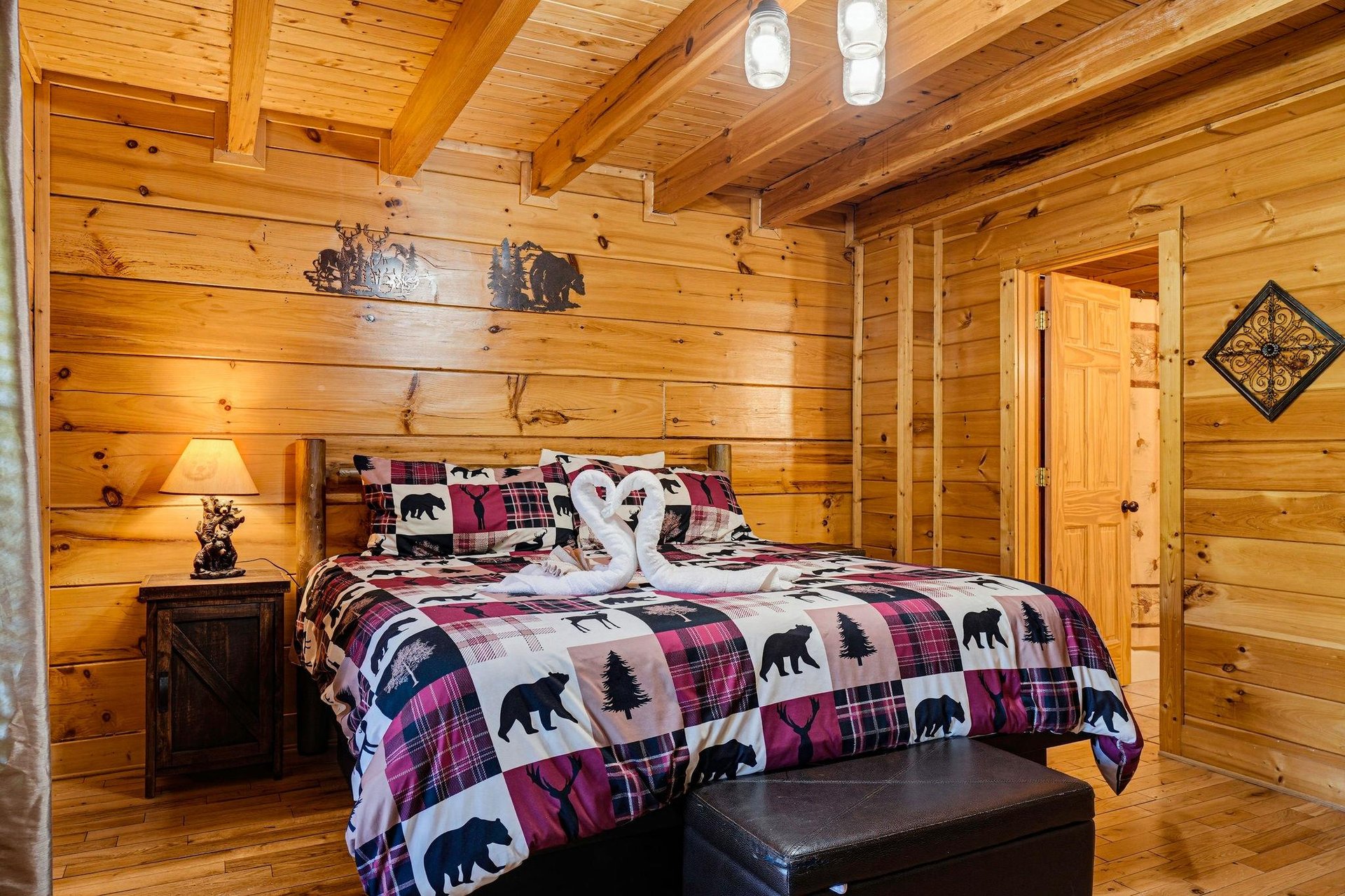 Cozy cabin bedroom with vaulted wood ceilings and rustic charm. Sink into the comfy bed under warm lighting and let the mountain lodge atmosphere surround you.