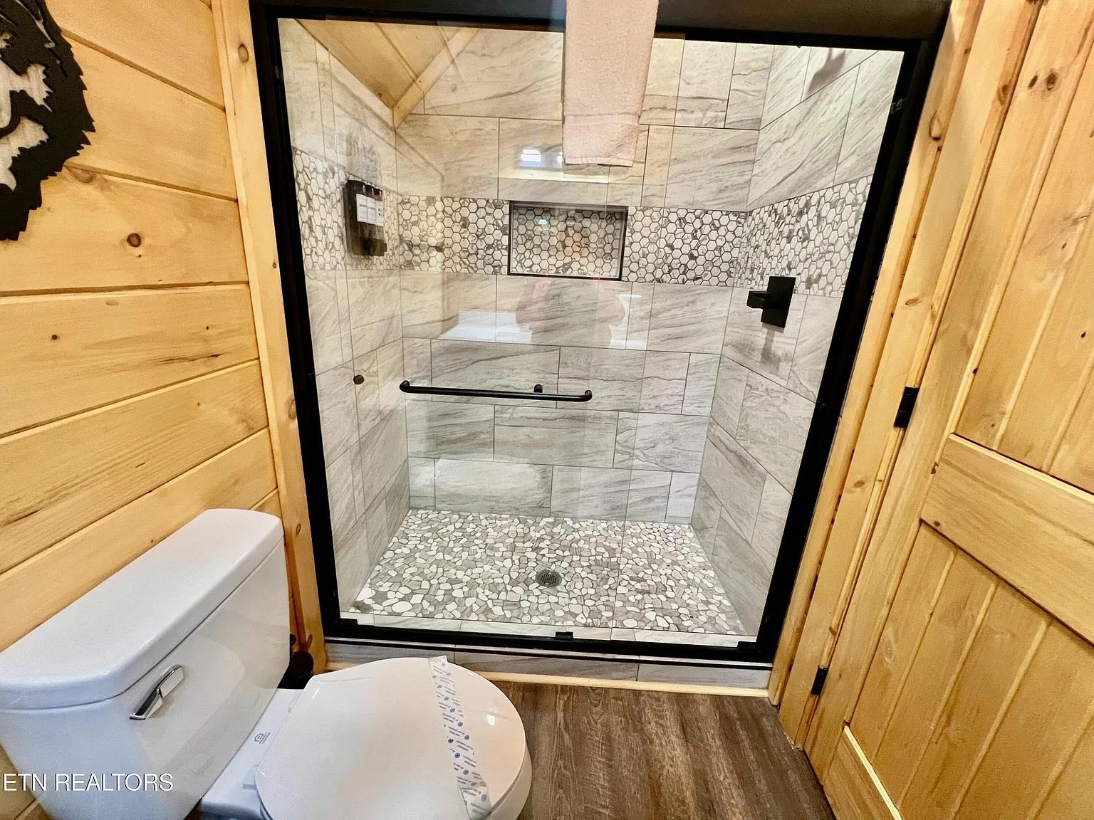 Unwind in your luxurious walkin shower featuring elegant marble tiles and stunning mosaic accents that create a spalike retreat.