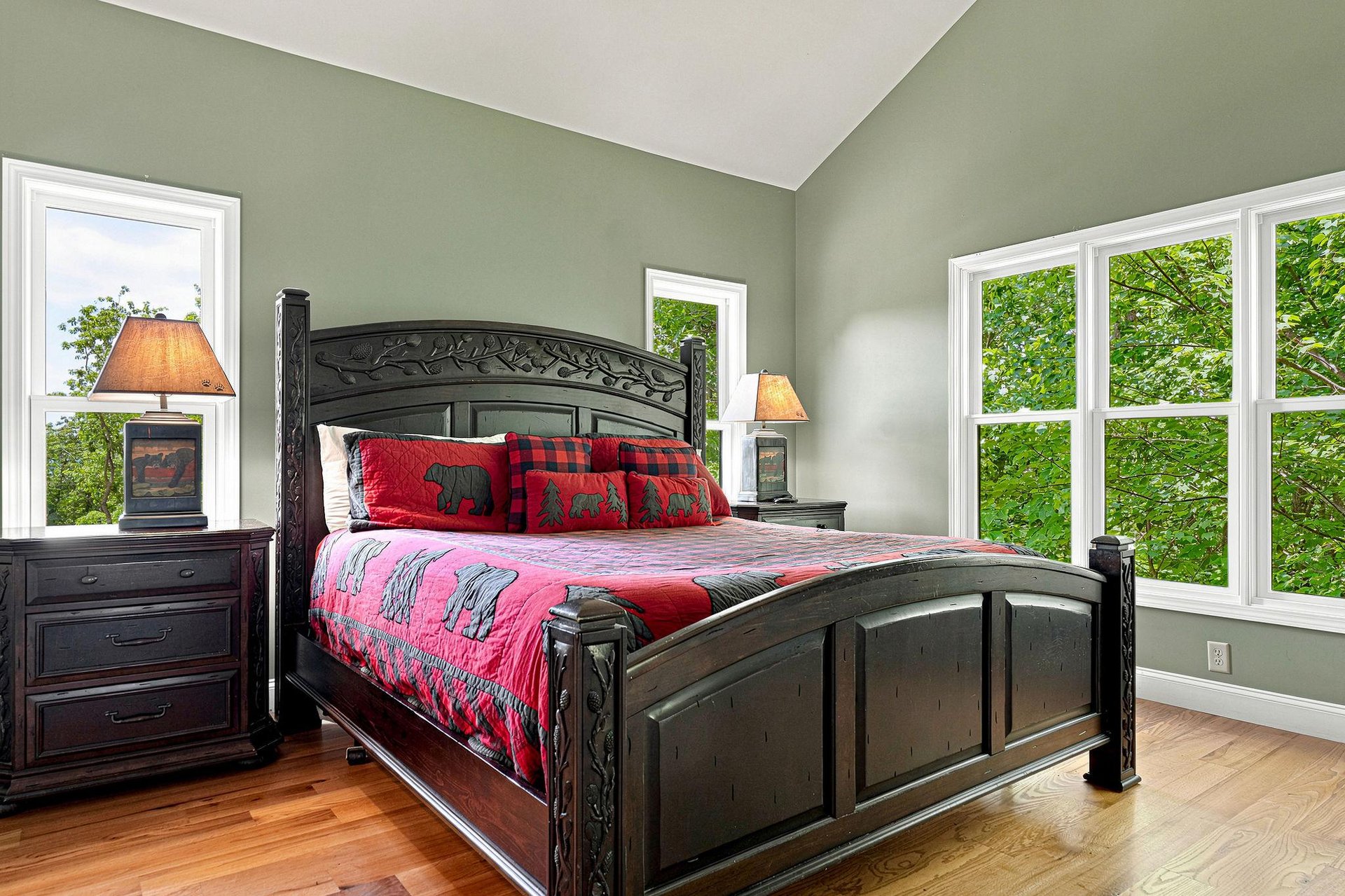 Unwind in your peaceful bedroom with its handsome carved bed, soothing sage walls, and bright windows framing lush greenery—your restful retreat awaits.