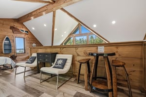 Relax in this charming loft with vaulted ceilings, warm wood beams, and cozy seating where you can unwind with lake views.