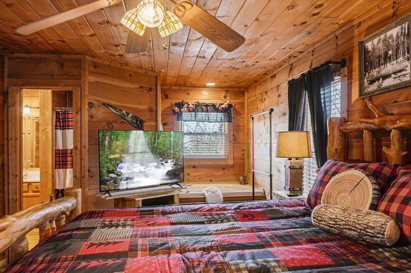 Unwind in your cozy log cabin bedroom with rustic charm, plaid bedding, and a smart TV for relaxing evenings.