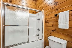 Refresh in your own cabinstyle bathroom featuring a tubshower combo, fresh towels, and warm woodpaneled walls that bring rustic comfort to your mountain retreat.