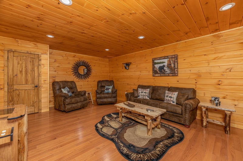 Sofa, two recliners, and video game in the lower living room at Js Hideaway, a 4 bedroom cabin rental located in Pigeon Forge