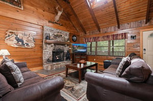Settle into plush leather sofas beside a stone fireplace under cathedral ceilings with natural wood beams. Large windows bring in forest views and daylight.